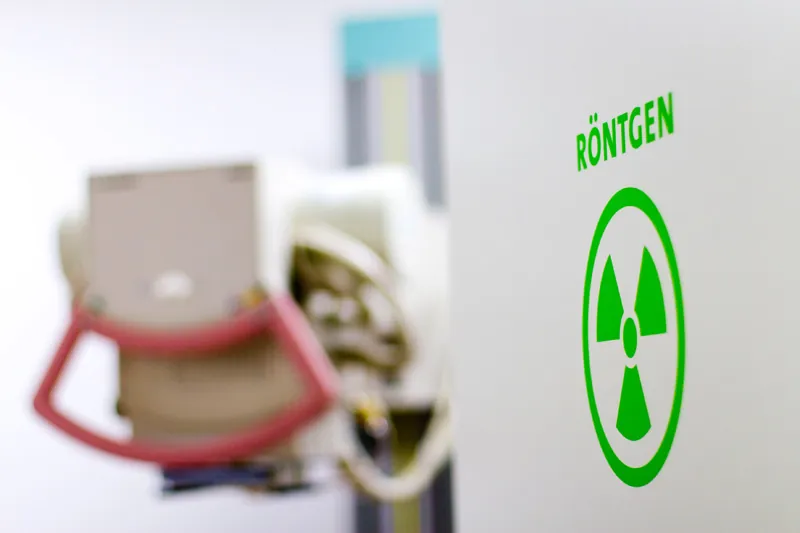 Röntgengerät vor der grün beschilderten Tür des Röntgenraums